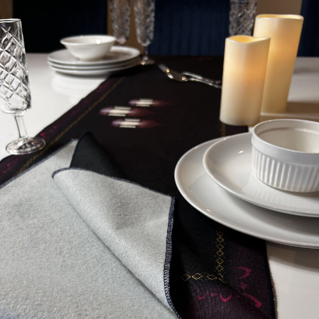 white tableware and candles on a black table runner
